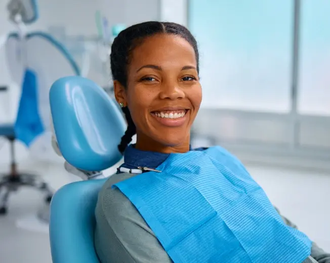 Smiling patient in dental chair wearing bib at San Pedro dental practice.
