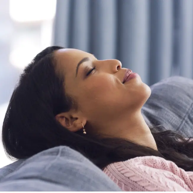 Woman relaxing with eyes closed, demonstrating restful sleep improved by dental sleep apnea treatment.